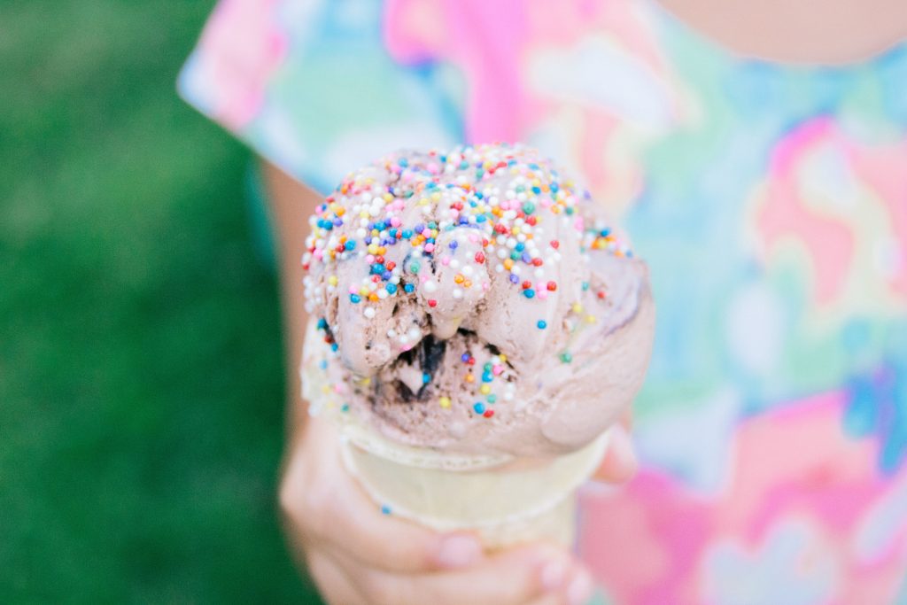 Hand Holding an ice-cream cone Lavender Flavor and colorful sprinkles .