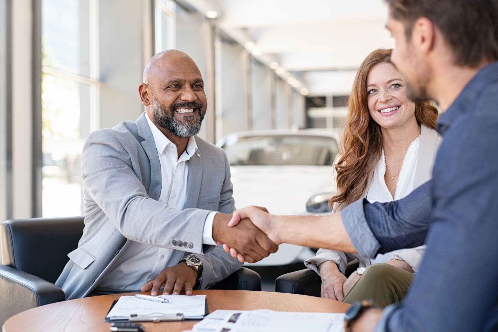 Sales manager shaking hands with customer in dealer showroom