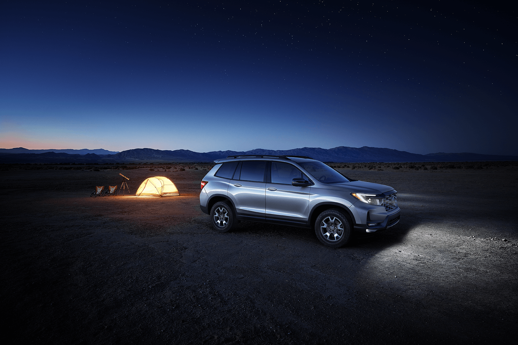 Honda SUV parked in desert while owners camp in tent